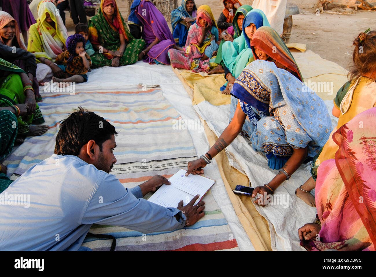 A FreshKart field officer reviewing a ledger with a rural women's lending group